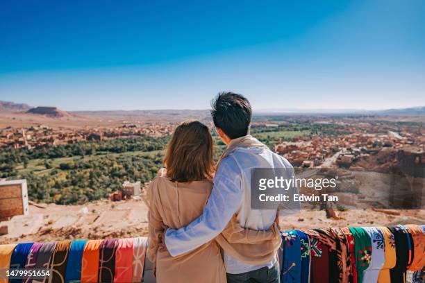 asiatisch-chinesisches paar tourist mit blick auf einen hohen winkel hügel in tinghir, marokko - date palm tree stock-fotos und bilder