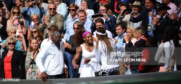 Player Serena Williams climbs up into the Royal Box to embrace her sister Venus WIlliams after her women's singles final victory over Poland's...