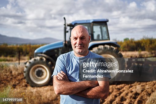 Farmer looking at camera with tractor in field