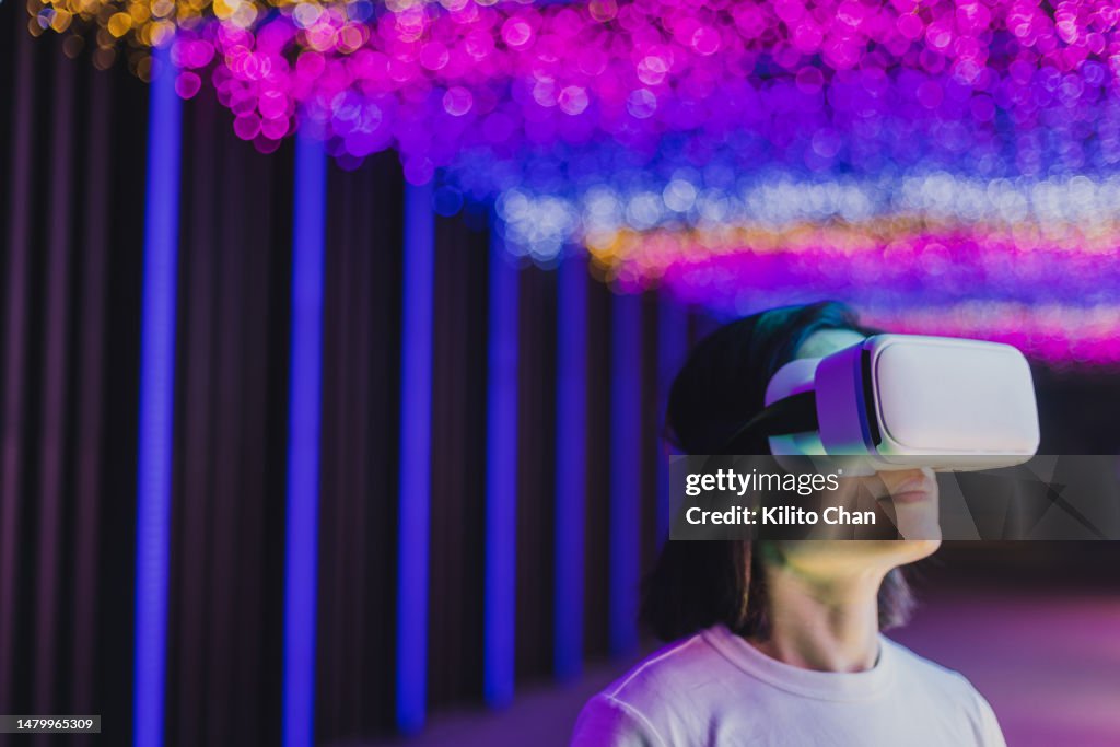 Asian woman using VR headset with dramatic light on the background