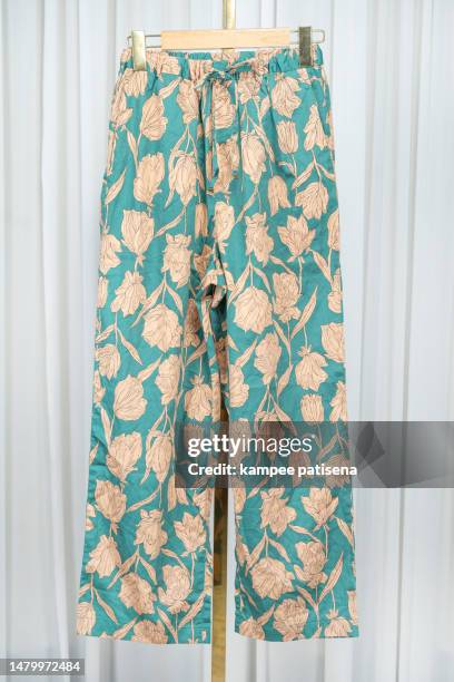 green floral pants hang on clothh anger stand - blue dress hanger stock pictures, royalty-free photos & images