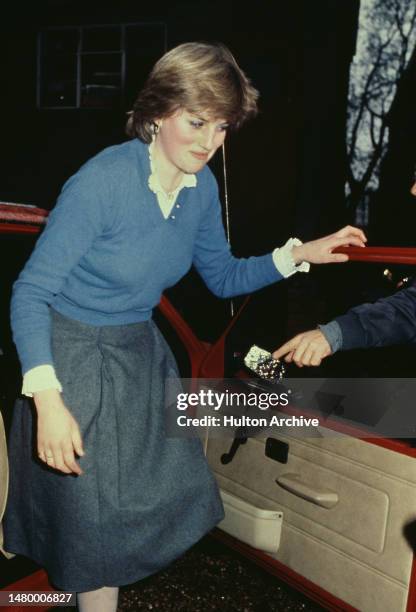 British Royal Lady Diana Spencer wearing a blue v-neck sweater over a white blouse, and a grey skirt as she gets out her Austin Metro car near her...