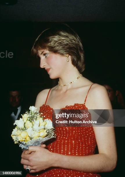 British Royal Lady Diana Spencer wearing a red-and-gold spangled chiffon Bellville Sassoon gown attends the premiere of the James Bond film 'For Your...