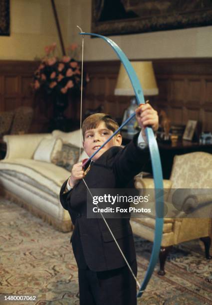 British Royal Prince Andrew takes aim with a blue bow and arrow at home in Windsor Castle, in Windsor, Berkshire, England, 1969.