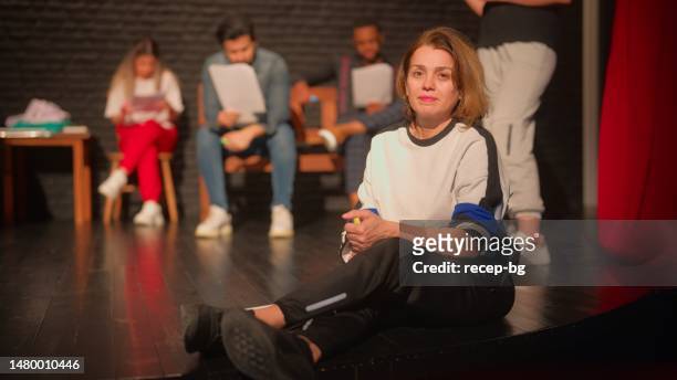 porträt einer theaterregisseurin, die auf dem boden der bühne sitzt - teacher studio portrait stock-fotos und bilder