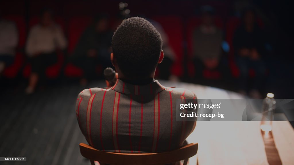 Black ethnic stand-up comedian talking on stage