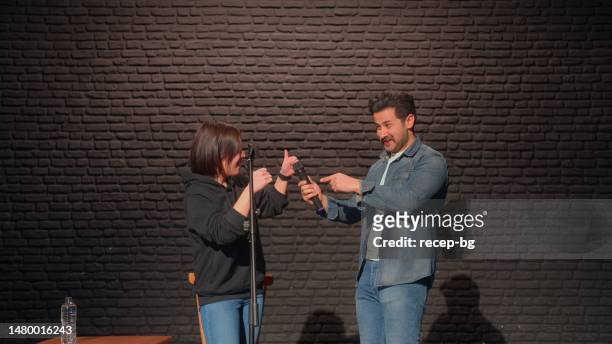 male stand-up comedian talking on stage and inviting one of the audiences to stage - comedian on stage stock pictures, royalty-free photos & images