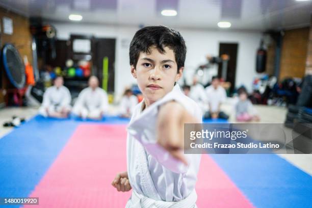 portrait of a child boy punching the air during a karate class - jujitsu stock pictures, royalty-free photos & images