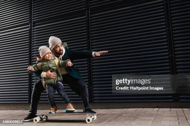 father teaching his son skateboarding. - familie mit zwei generationen stock-fotos und bilder