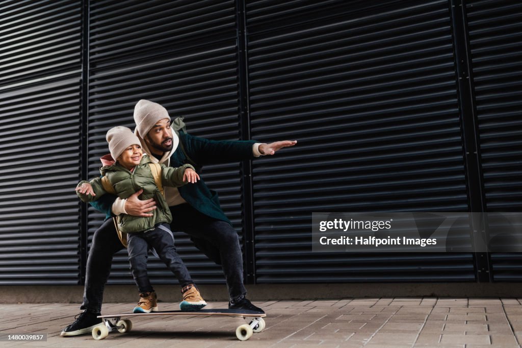 Father teaching his son skateboarding.