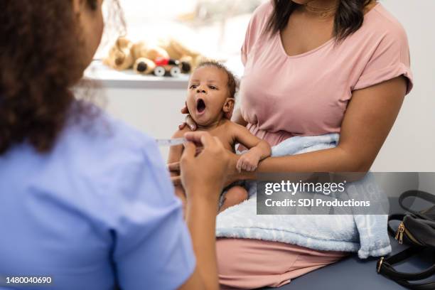 newborn boy yawns during his medical examination at the pediatric office - pediatric nurse stock pictures, royalty-free photos & images