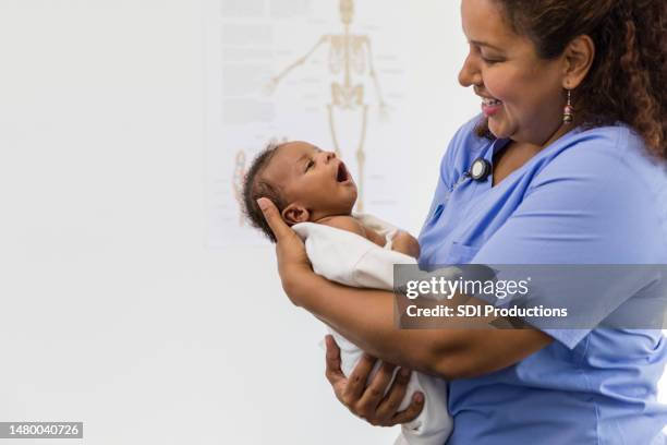 la enfermera sonríe mientras admira al niño recién nacido - new born black babies fotografías e imágenes de stock