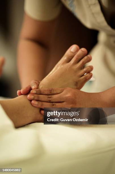 thai traditional foot massage,physiotherapist giving foot massage to a woman,the hands of the massage therapist massage the foot in the process of a wellness massage of the whole body, foot massage as a means to improve the overall health of the body - massage therapy stock pictures, royalty-free photos & images