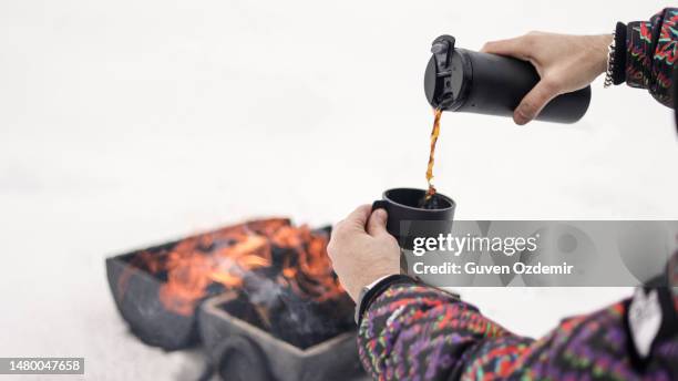 close-up do homem com garrafa térmica derramando café, close-up do homem bebendo café na floresta de inverno, fross com bebida quente, campista de inverno bebendo café quente de sua garrafa térmica em tempo nevado, café quente com fogueira - tea hot drink - fotografias e filmes do acervo