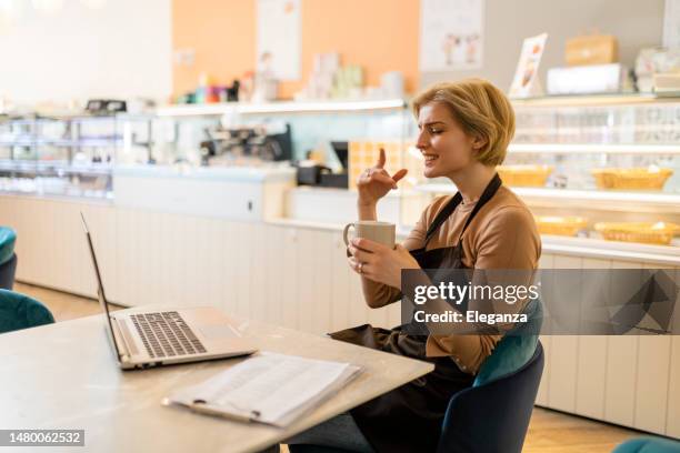stressed female owner of cake shop working on laptop - overworked waitress stock pictures, royalty-free photos & images