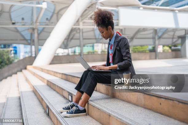a young woman is using her laptop to make a video call with a client or business team to discuss a business project outside of a modern business office. - kontinuität stock-fotos und bilder