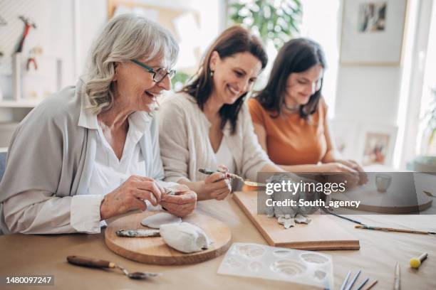 female siblings molding clay together - active seniors group stock pictures, royalty-free photos & images