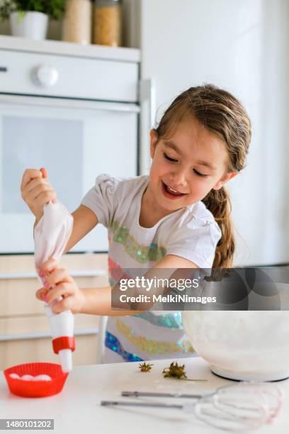 niña divirtiéndose con manga pastelera en la cocina - cupcakes girls fotografías e imágenes de stock