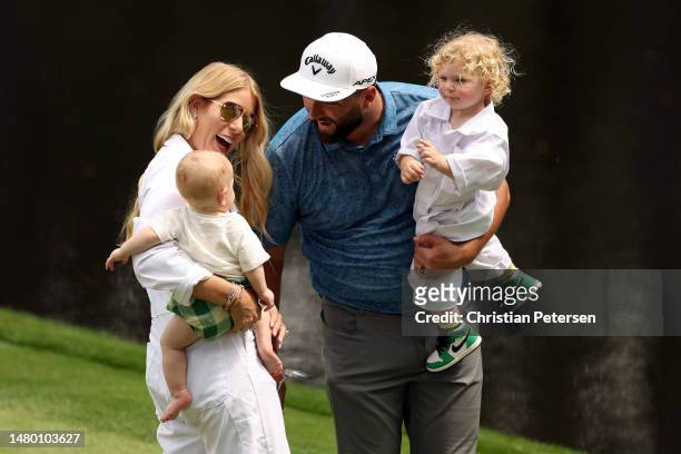 Jon Rahm of Spain and his wife, Kelley, and his children Eneko and Kepa, react on the ninth green during the Par 3 contest prior to the 2023 Masters...