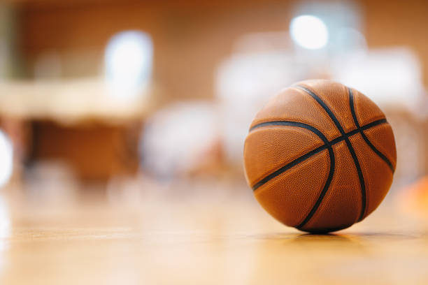 close-up image of basketball ball over floor in the gym. orange basketball ball on wooden parquet. - basketball stock pictures, royalty-free photos & images