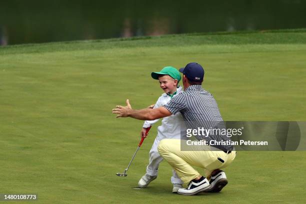 Billy Horschel of the United States hugs his son Axel Brooks Horschel on the ninth green during the Par 3 contest prior to the 2023 Masters...