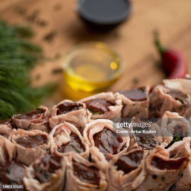 liver shish kebab wrapped in lard on skewers. raw kebab lies on table with spices, vegetables and herbs. azerbaijani cuisine. eastern cuisine. top view. close-up. - carne di scarto foto e immagini stock