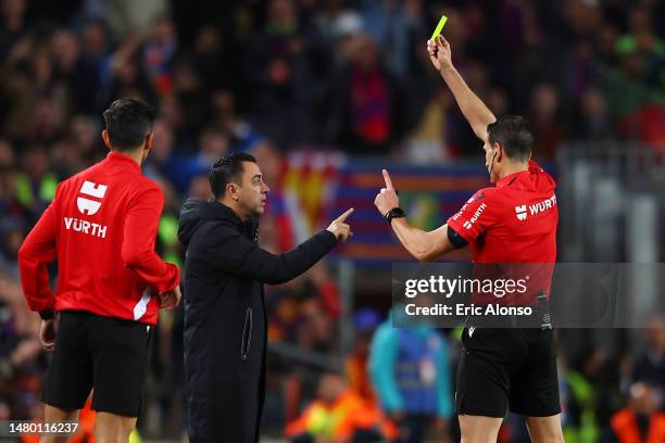 Referee Jose Munuera Montero shows a yellow card to Xavi, Head Coach of FC Barcelona, during the Copa Del Rey Semi Final Second Leg match between FC...
