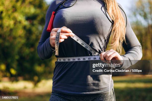 athletic slim woman measuring her waist by measure tape after workout outdoors,romania - overthrow stock pictures, royalty-free photos & images