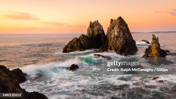 scenic view of rocks in sea against sky during sunset,wallaga lake,new south wales,australia - felsformation stock-fotos und bilder