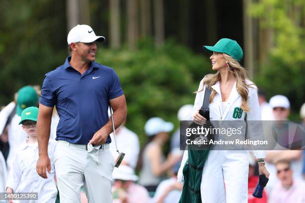 Brooks Koepka of the United States looks on with his wife, Jena Sims Koepka, during the Par 3 contest prior to the 2023 Masters Tournament at Augusta...