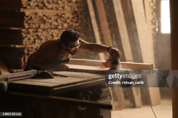 young carpenter using sander while working on a piece of wood. - sawdust stock pictures, royalty-free photos & images