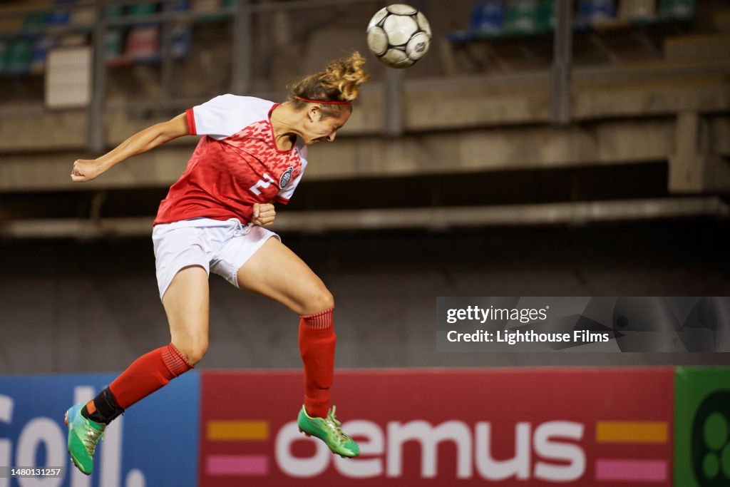 A female winger meets a header in mid air for a shot on goal