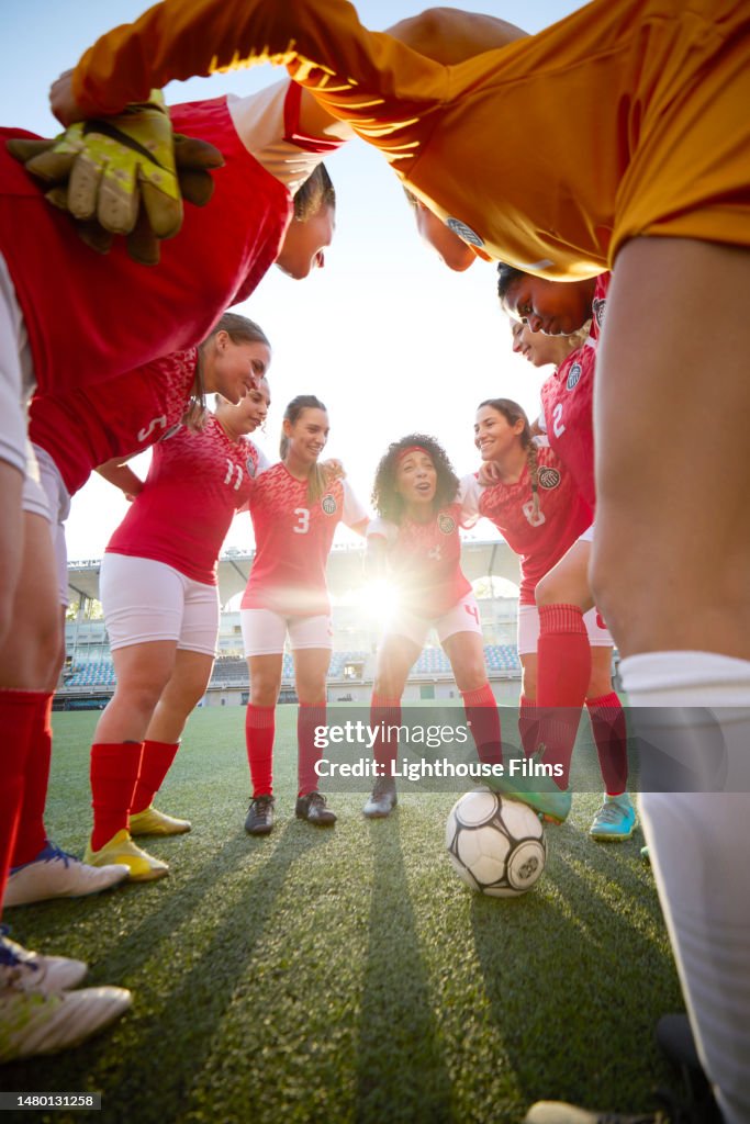 Motivated huddle of professional women soccer players meet to strategize on the field
