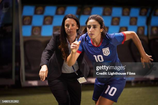 a female athlete sprints onto the field after discussing game play with her coach - middenvelder atleet stockfoto's en -beelden