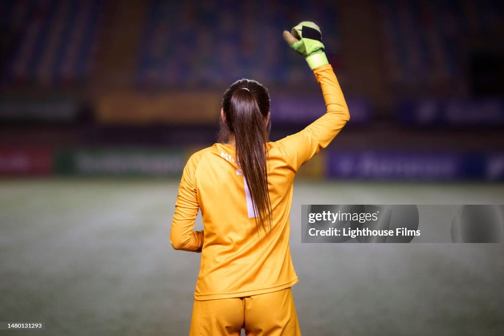 Rear view of a female soccer goalie as she raises her fist in the air before a game