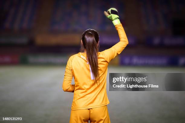 rear view of a female soccer goalie as she raises her fist in the air before a game - women's football stock pictures, royalty-free photos & images