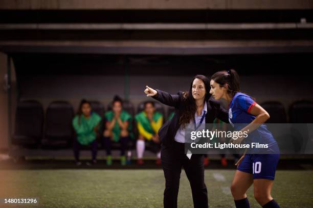 strong female soccer coach gives direction to her star player during a close soccer game - mentor - fotografias e filmes do acervo