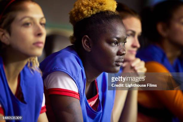 distressed female soccer player looks onto the field as her team plays - sub 20 stockfoto's en -beelden