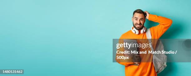 confused male student looking puzzled and scratching head,holding - hipster beard plain background stock-fotos und bilder