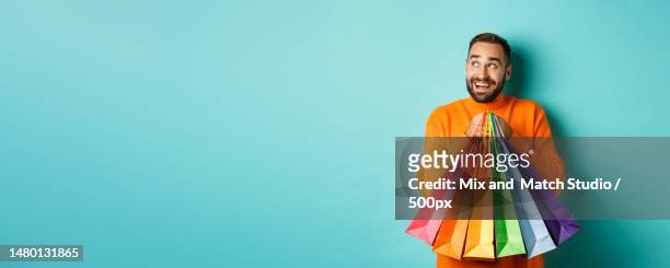 happy caucasian man in orange sweater,looking left and imaging - hipster beard plain background stock-fotos und bilder