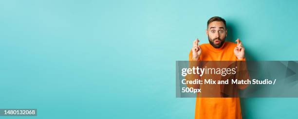 hopeful man waiting with excitement,holding fingers crossed and - hipster beard plain background stock-fotos und bilder