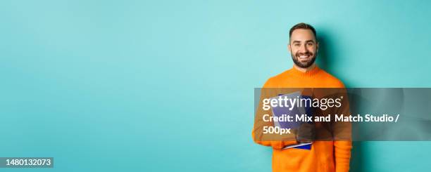 education smiling bearded man holding notebooks and smiling,going on - hipster beard plain background stock-fotos und bilder