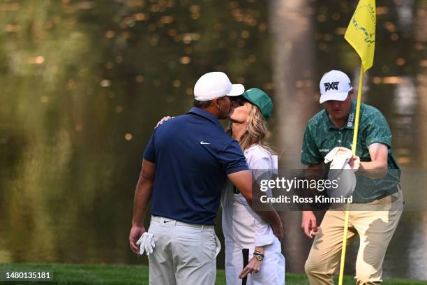 Brooks Koepka of the United States kisses his wife, Jena Sims Koepka, on the ninth green during the Par 3 contest prior to the 2023 Masters...