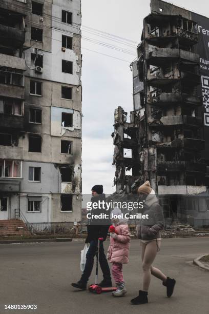 ukrainian family walking past damaged apartment building in borodyanka - ukraine war bildbanksfoton och bilder