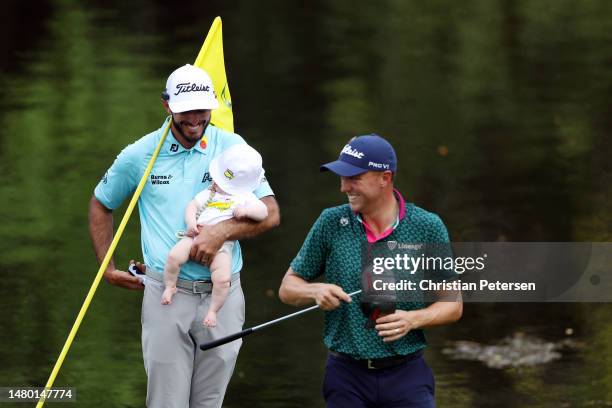 Max Homa of the United States holds his son, Cam Homa, laugh with Justin Thomas of the United States on the ninth green during the Par 3 contest...