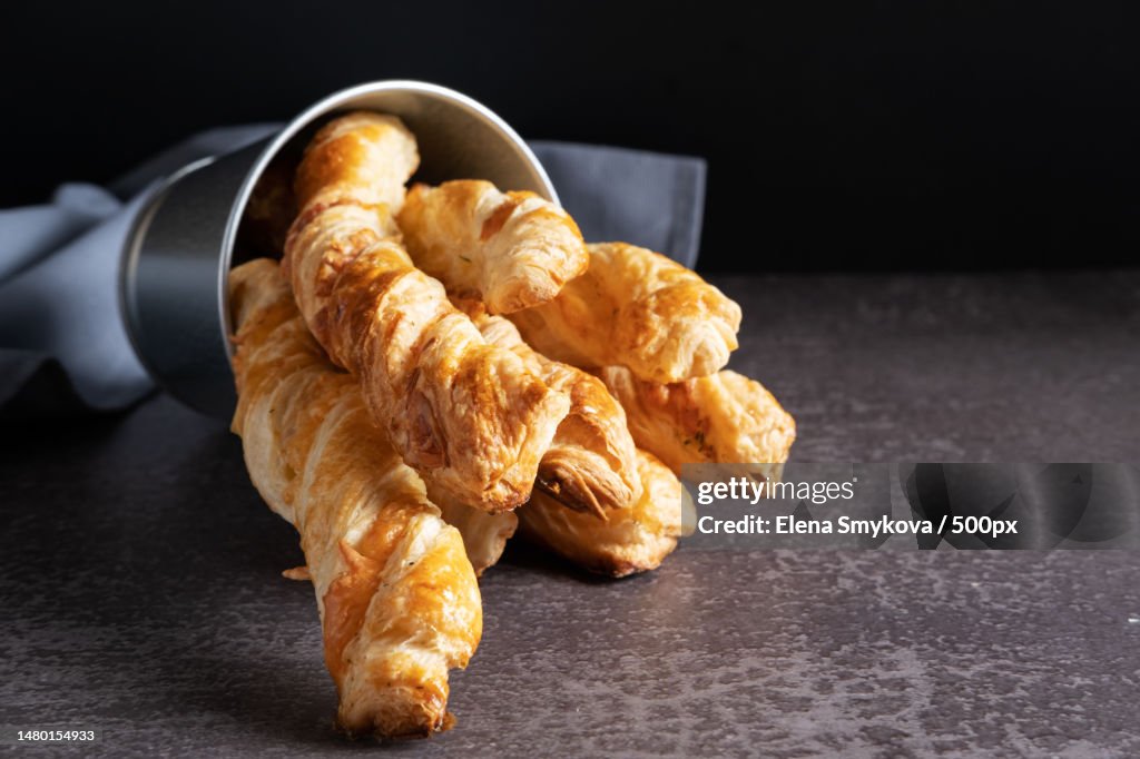 Cheese sticks made of puff pastry lie in a metal bucket on a dark table,Moscow,Russia