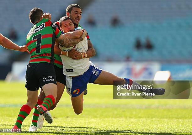 Dylan Farrell of the Rabbitohs tackles Timana Tahu of the Knights during the round 18 NRL match between the South Sydney Rabbitohs and the Newcastle...