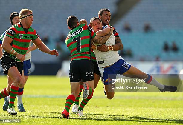 Dylan Farrell of the Rabbitohs tackles Timana Tahu of the Knights during the round 18 NRL match between the South Sydney Rabbitohs and the Newcastle...