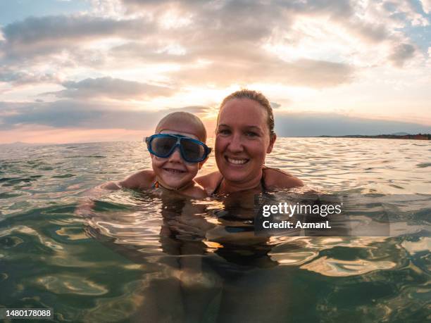 happy caucasian single mother and her son swimming in the water while on summer holidays - happy holidays family stock pictures, royalty-free photos & images