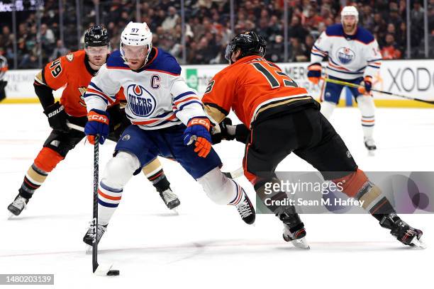 Connor McDavid of the Edmonton Oilers controls the puck past the defense of Simon Benoit and Max Jones of the Anaheim Ducks during the first period...